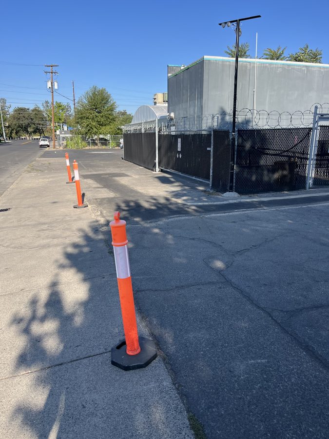 Worn, oxidized commercial parking lot with faded gray asphalt and surface cracks before sealcoating on Market Street in Medford, Oregon