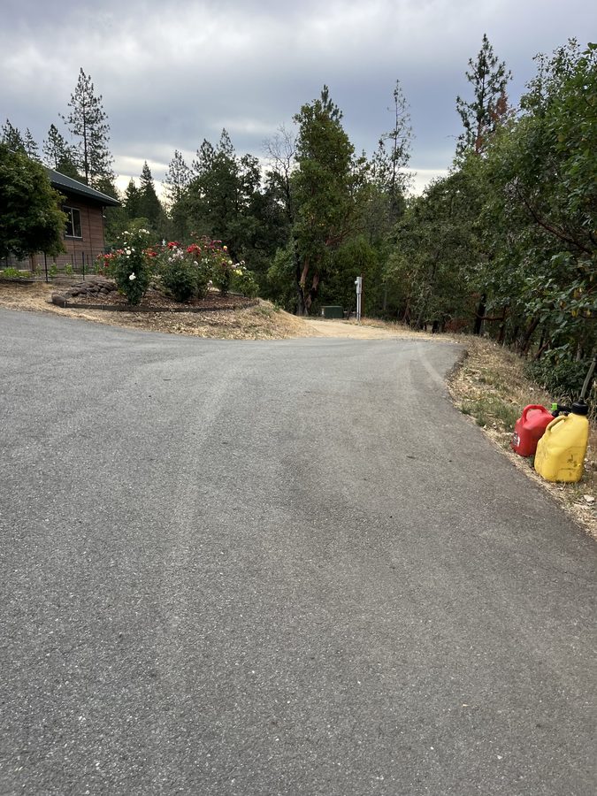 Freshly sealcoated residential driveway running past a flower garden and trees on Seclusion Loop in Grants Pass, Oregon